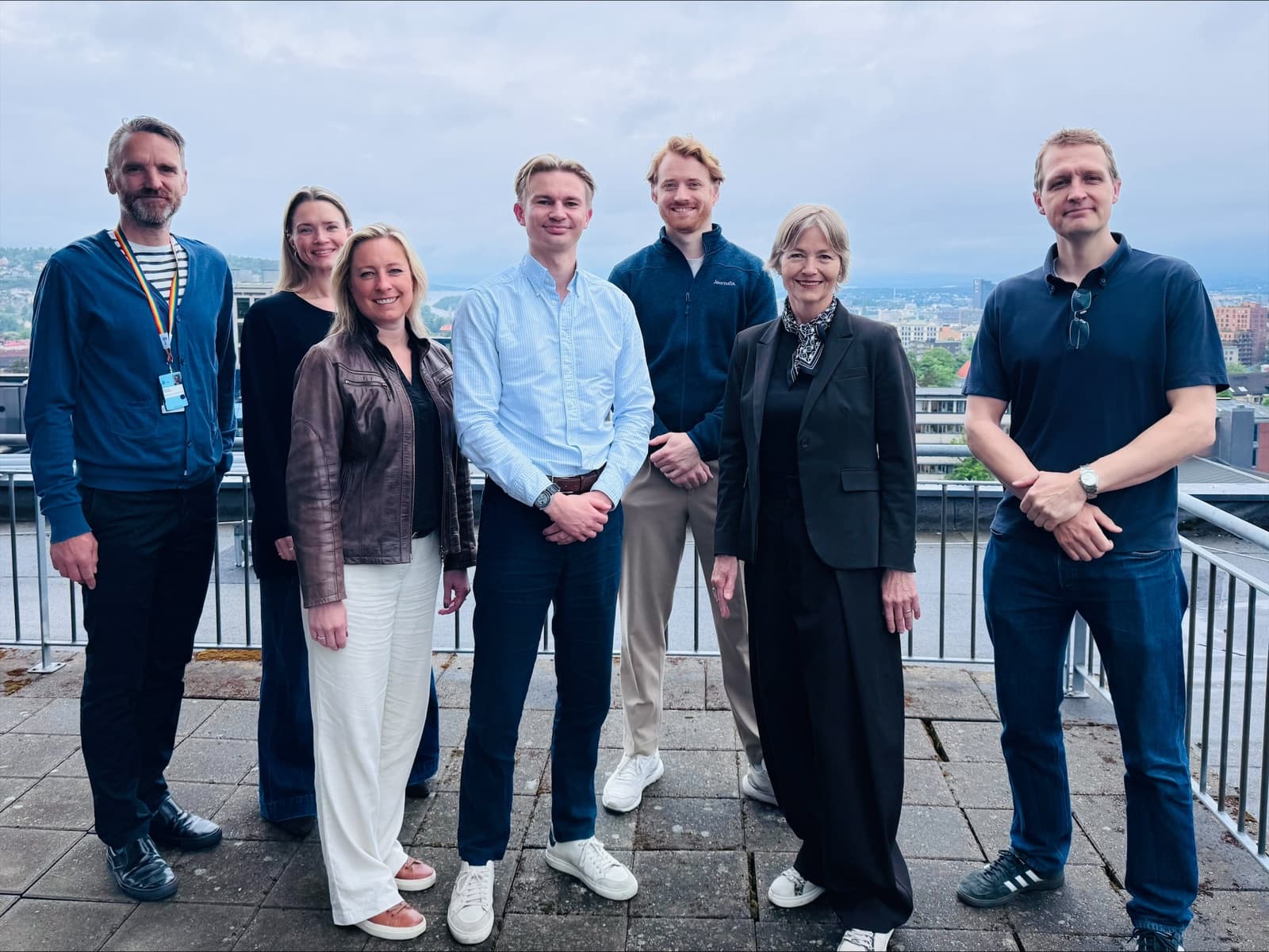 The Journalia team and Oslo municipality representatives on a rooftop terrace with the Oslo skyline behind them.